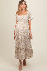 woman wearing a floral print maternity maxi dress with puff sleeves and a smocked bodice, showcasing her baby bump