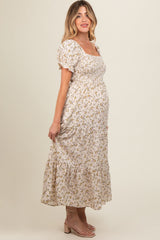 woman wearing a cream floral maternity maxi dress with puff sleeves and a fitted bodice, showing her baby bump