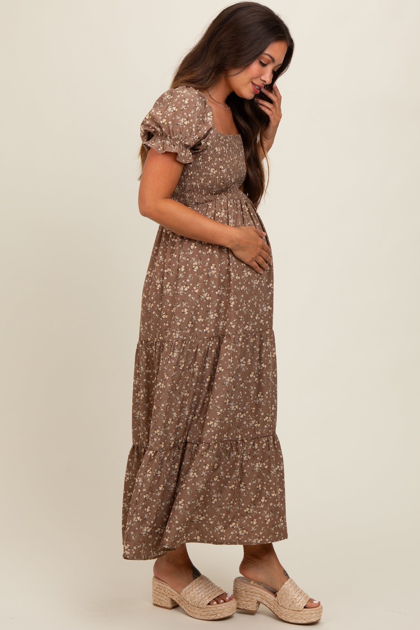 woman wearing a brown floral maternity maxi dress and holding her baby bump