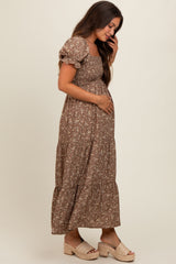 woman wearing a brown floral maternity maxi dress and holding her baby bump