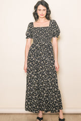woman wearing a black floral maxi dress with short puff sleeves and a square neckline