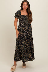 woman wearing a black floral maternity maxi dress with short puff sleeves and a smocked bodice