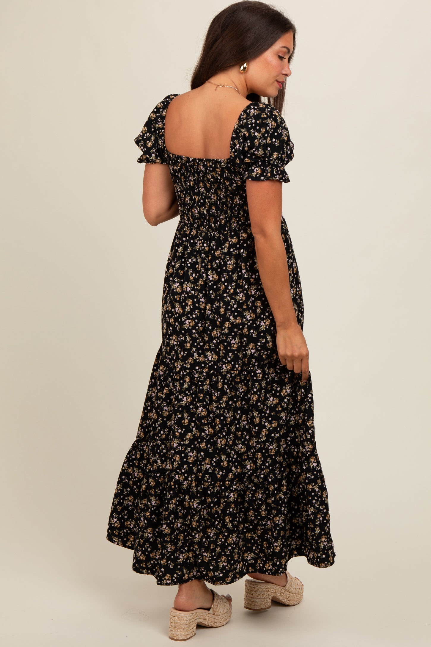 woman wearing a black floral maternity maxi dress with short puff sleeves and a smocked back