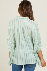woman wearing a green striped maternity top with a relaxed fit and back pleating, styled with blue jeans