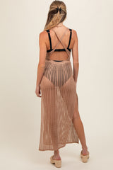 woman wearing a tan long crochet maternity cover-up with an open back and side slits