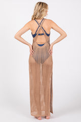 woman wearing a long tan crochet cover-up over a navy swimsuit, showing a crisscross back design and side slits