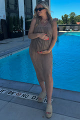 woman wearing a tan crochet maternity dress at a pool, cradling her baby bump