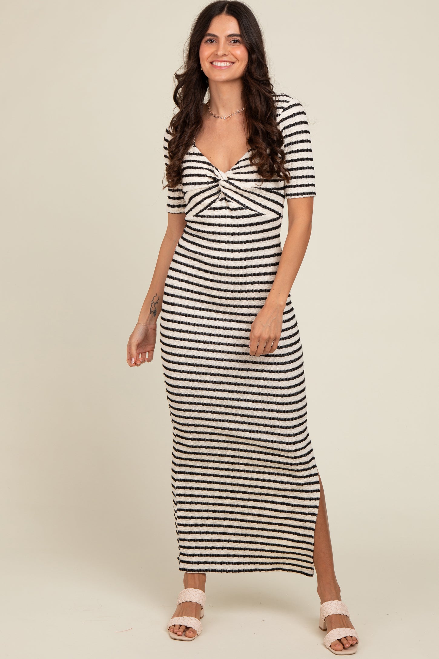 woman wearing a black and white striped midi dress with a twisted front and side slit