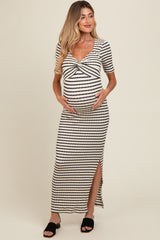 woman wearing a striped maternity maxi dress with a twisted front detail and side slit, holding her baby bump