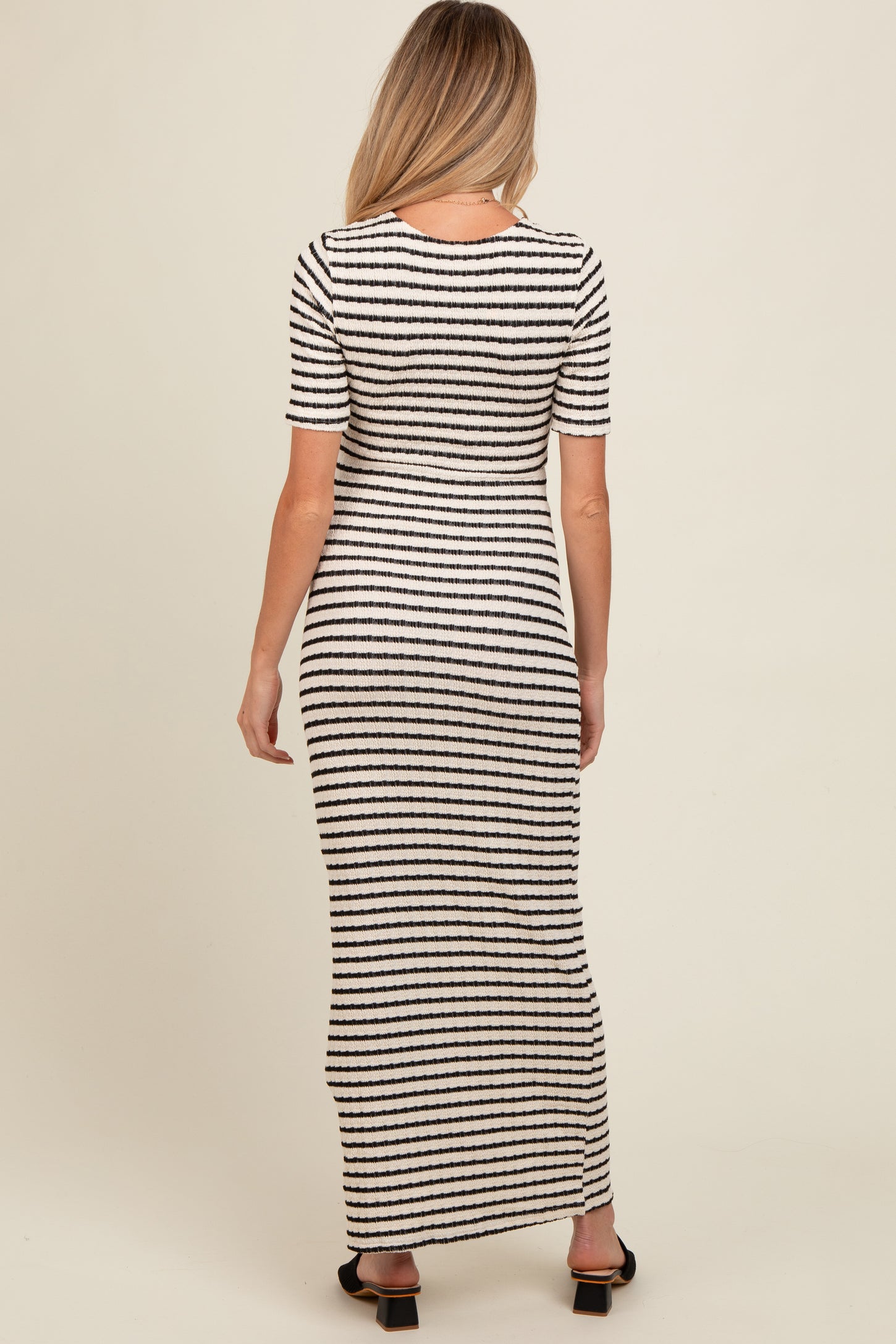 woman wearing a black and white striped maternity maxi dress from the back