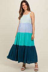 woman wearing a colorful tiered maxi maternity dress in shades of blue and green, showcasing a baby bump