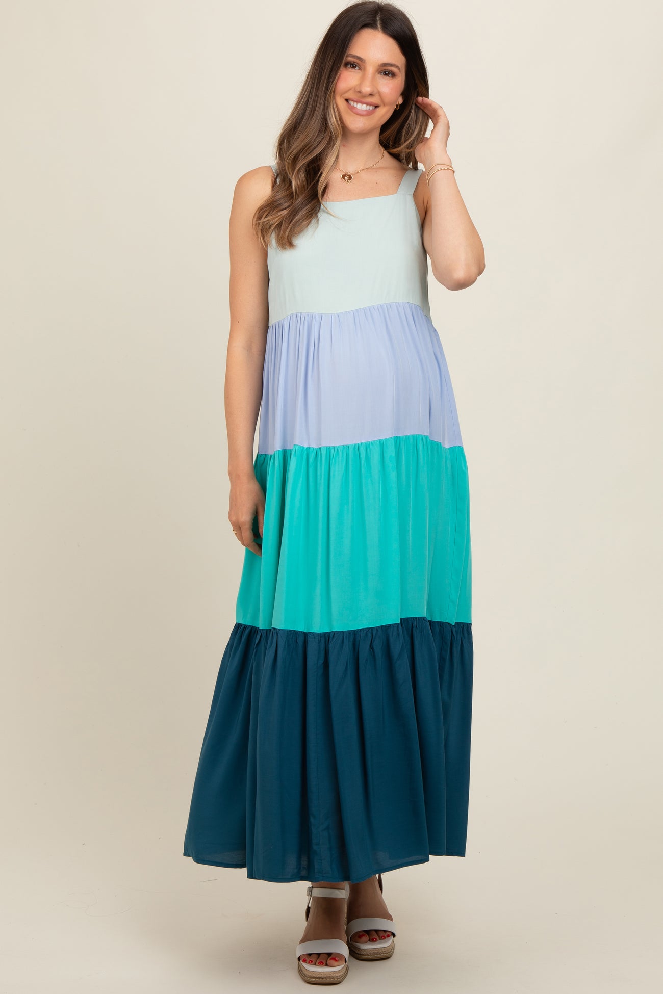 woman wearing a multi-colored maternity maxi dress with blue and green tiers and a flowy bottom