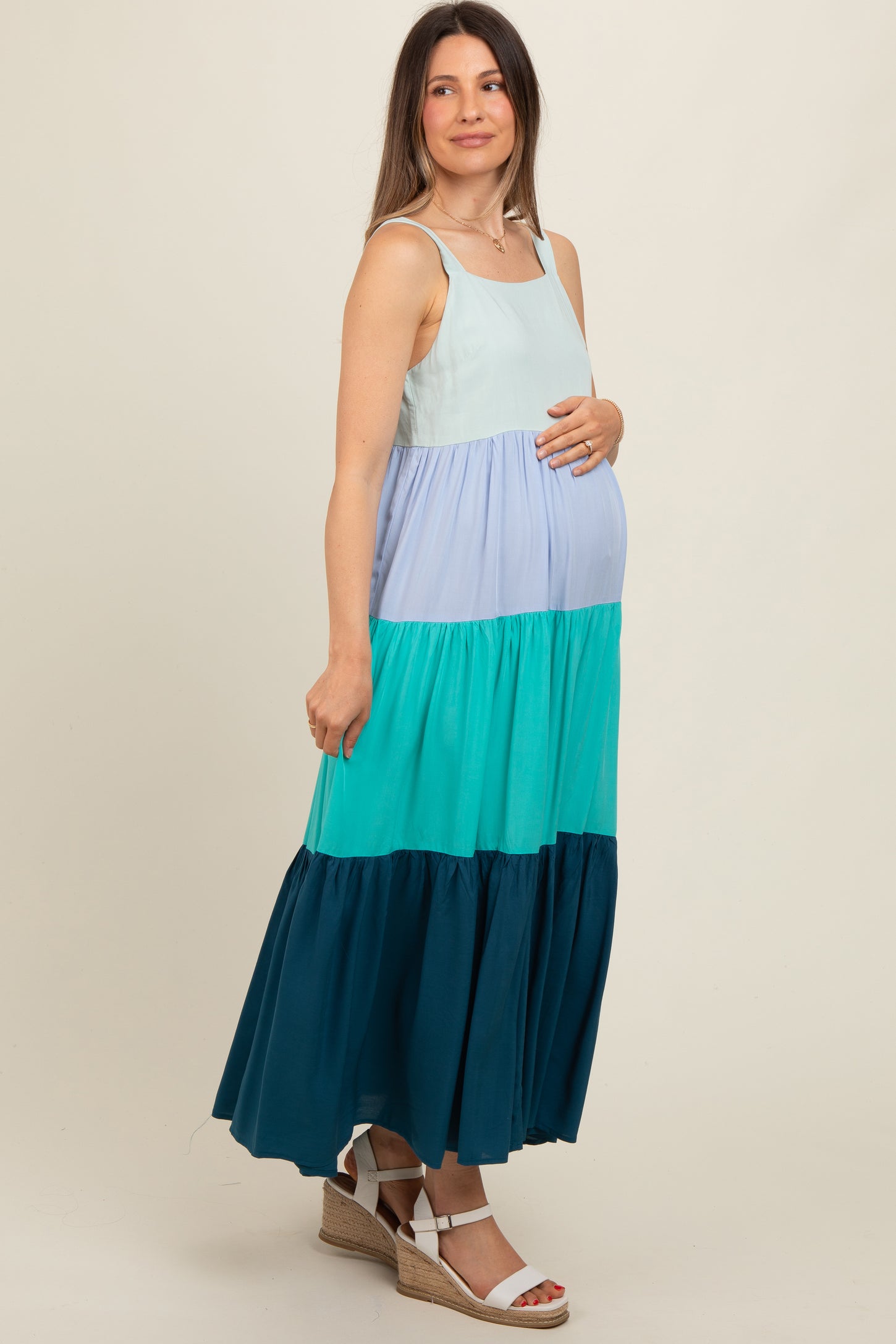 woman wearing a multicolored sleeveless maternity maxi dress and holding her baby bump