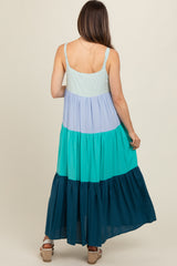 woman wearing a color-blocked maternity maxi dress in light blue, lavender, teal, and dark blue, showing the back view