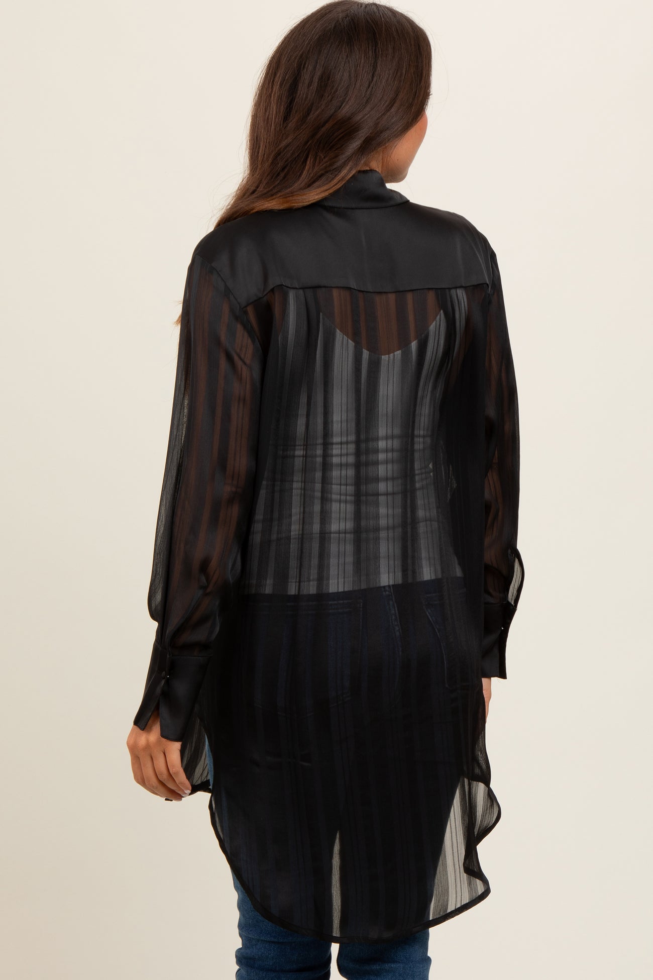woman wearing a black sheer maternity top with a long back and striped pattern