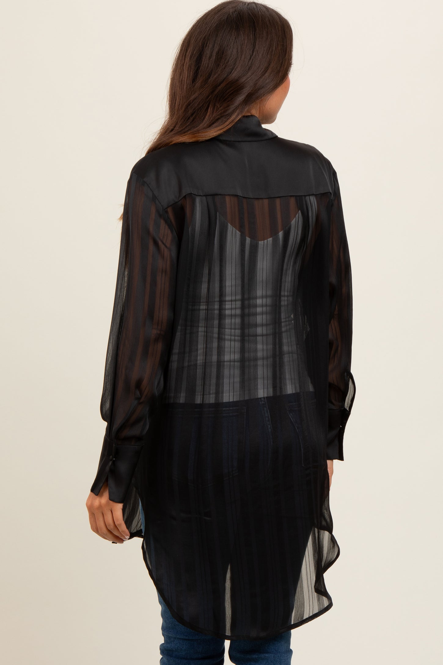 woman wearing a black sheer maternity top with a long back and striped pattern