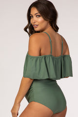 woman wearing a green off-the-shoulder maternity swimsuit with ruffle detail and adjustable straps