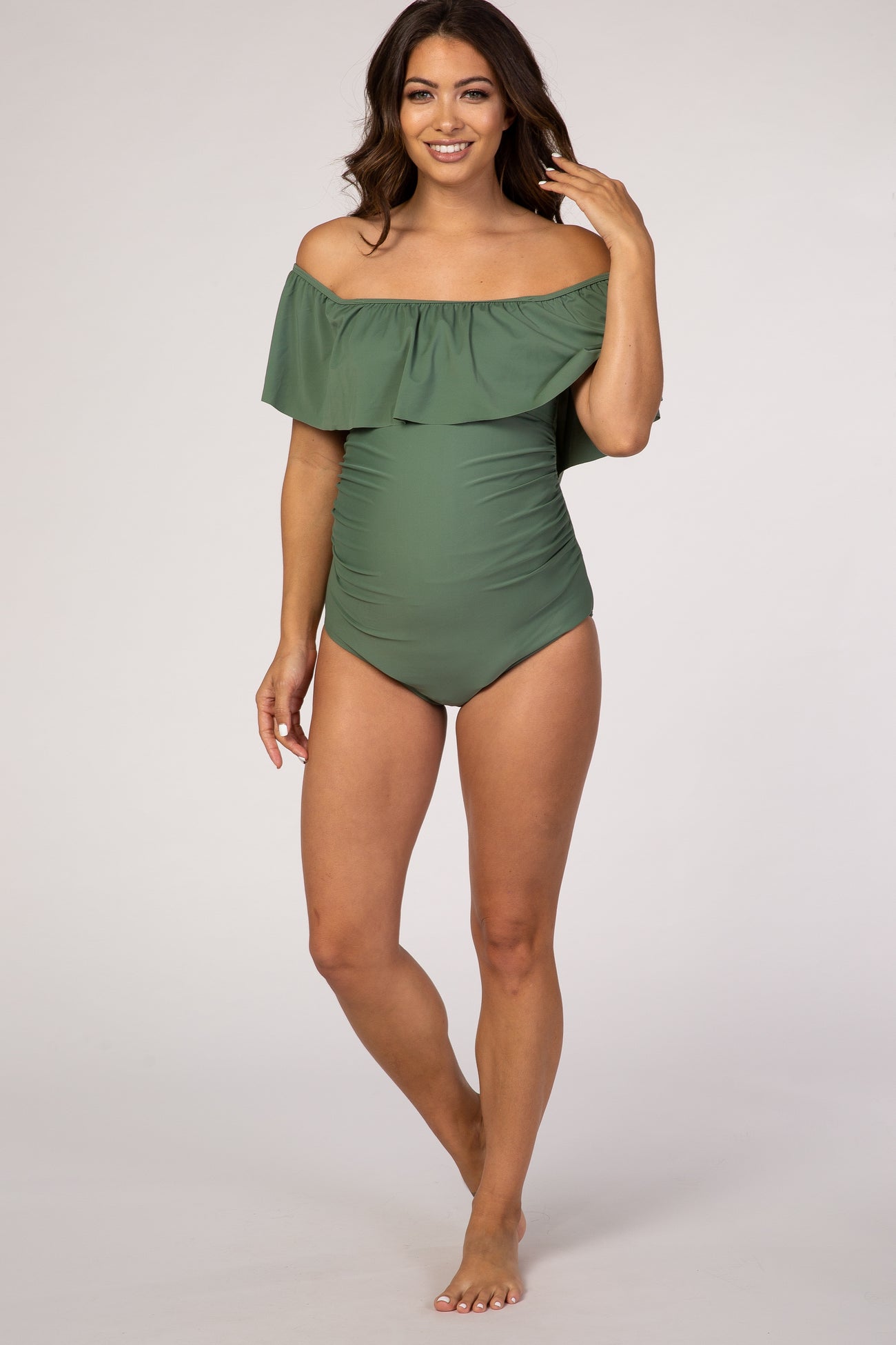 woman wearing a green off-the-shoulder maternity swimsuit with ruffle detailing and a fitted bodice