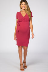 woman wearing a raspberry short sleeve maternity dress with a wrap tie detail and visible baby bump